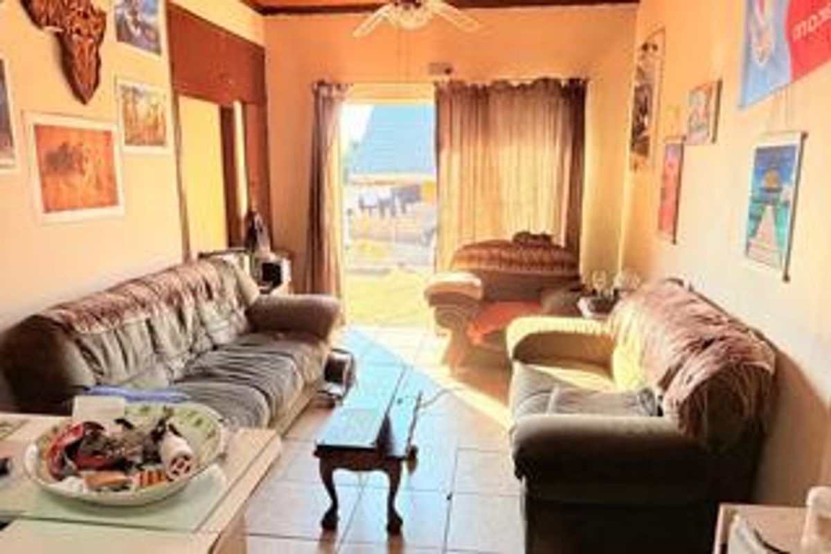 A living room featuring tiled flooring, a ceiling fan, and a sliding glass door providing access to the exterior.