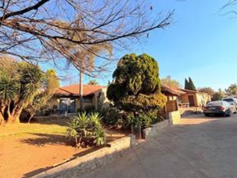 Front exterior view of the house featuring a tiled roof, paved driveway, and established garden area.