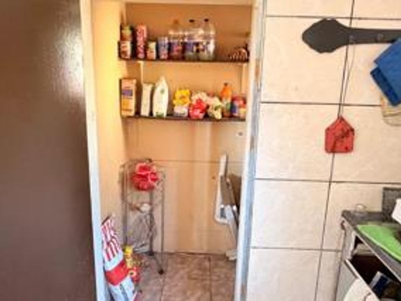 A small scullery or pantry area featuring built-in shelving and tiled wall finishes, providing functional storage space adjacent to the main kitchen area.