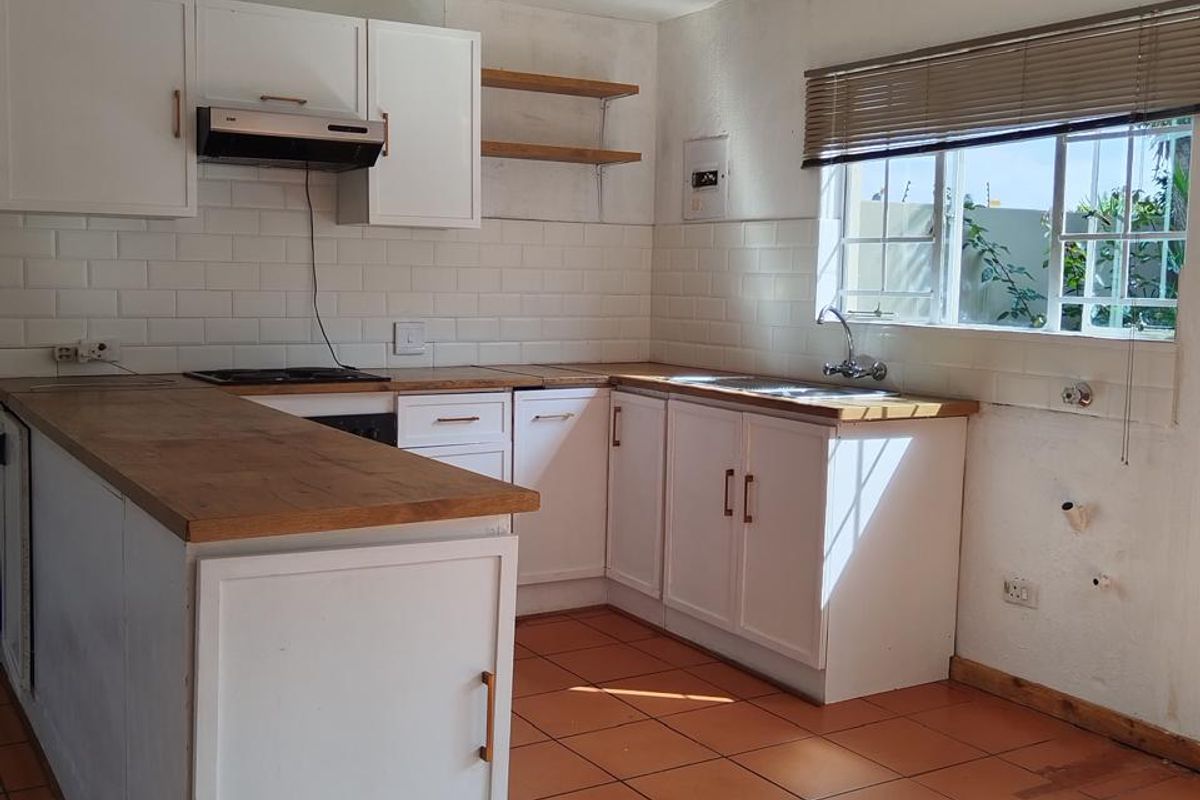 A functional kitchen featuring white cabinetry, wooden countertops, subway tile backsplash, and ceramic floor tiles, offering a clean canvas for potential updates.
