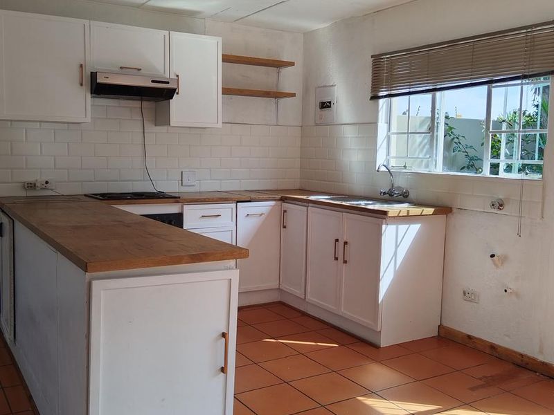 A functional kitchen featuring white cabinetry, wooden countertops, subway tile backsplash, and ceramic floor tiles, offering a clean canvas for potential updates.