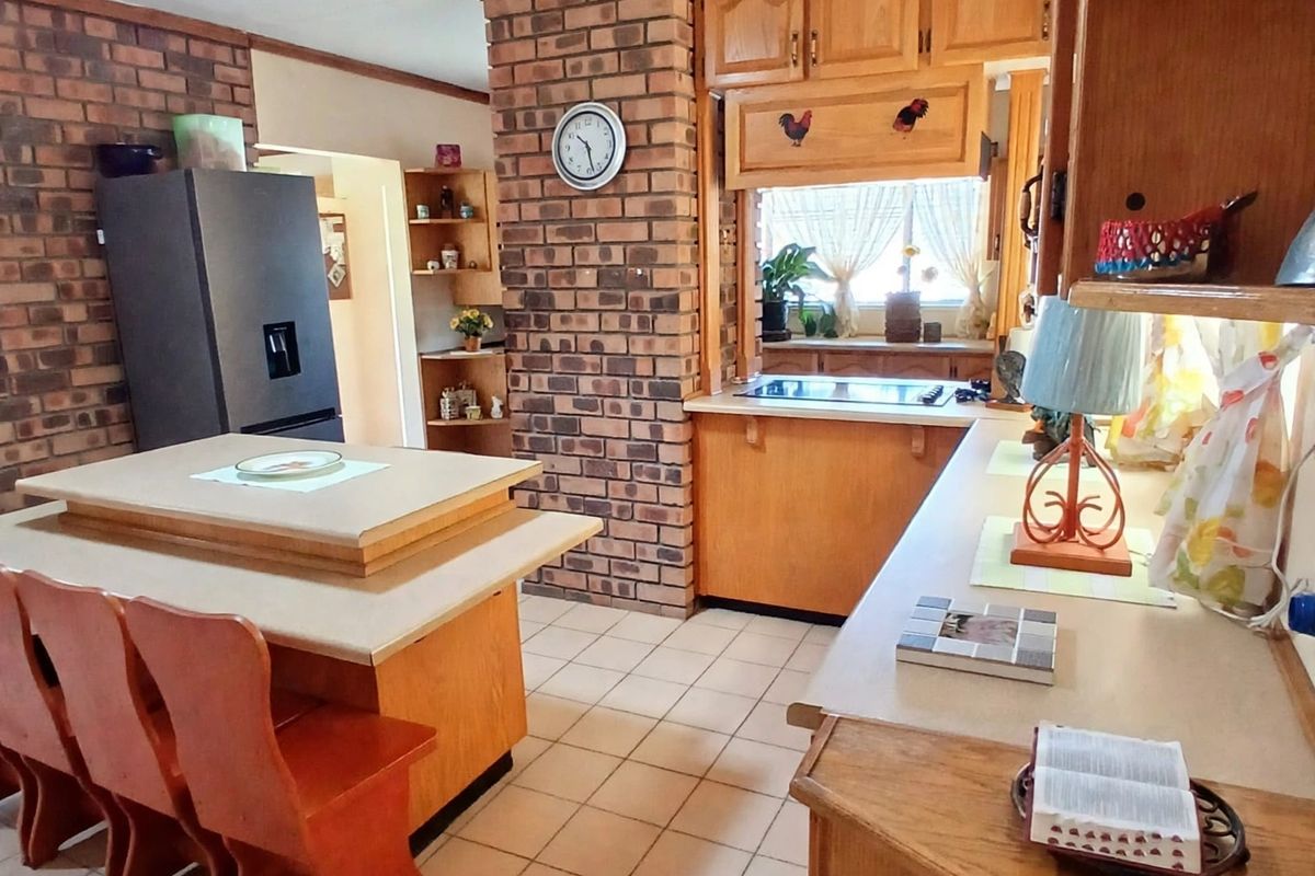 A rustic kitchen featuring exposed brick walls, wooden cabinetry, and a central island, offering a warm, traditional aesthetic with potential for modern updates.