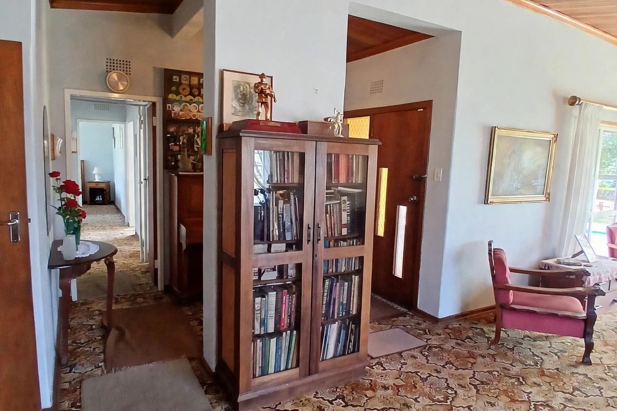 Living area featuring a timber tongue and groove ceiling, patterned carpeting, and traditional archway transitions leading to the hallway and entrance.