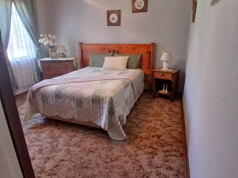 A bedroom featuring dated patterned carpet flooring and a central ceiling light fixture with a decorative rose.