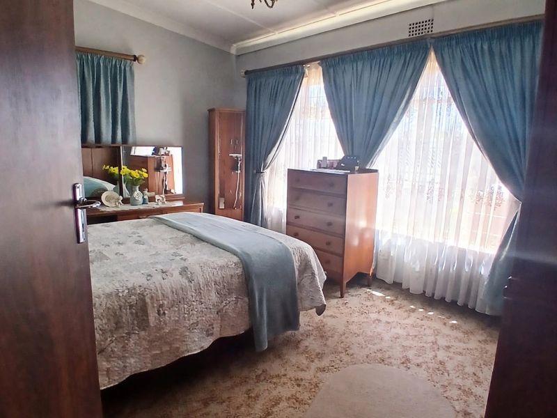 A bedroom featuring a coved ceiling, fitted carpeting, and large windows with curtain rails, offering a traditional layout ready for modernization.
