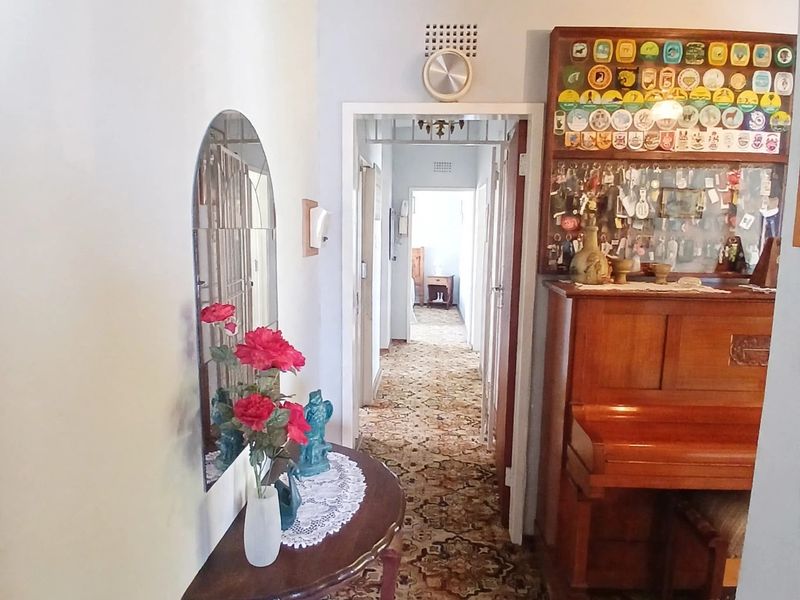 A narrow hallway featuring a vaulted timber ceiling and patterned carpet flooring, providing access to the interior rooms of the home.