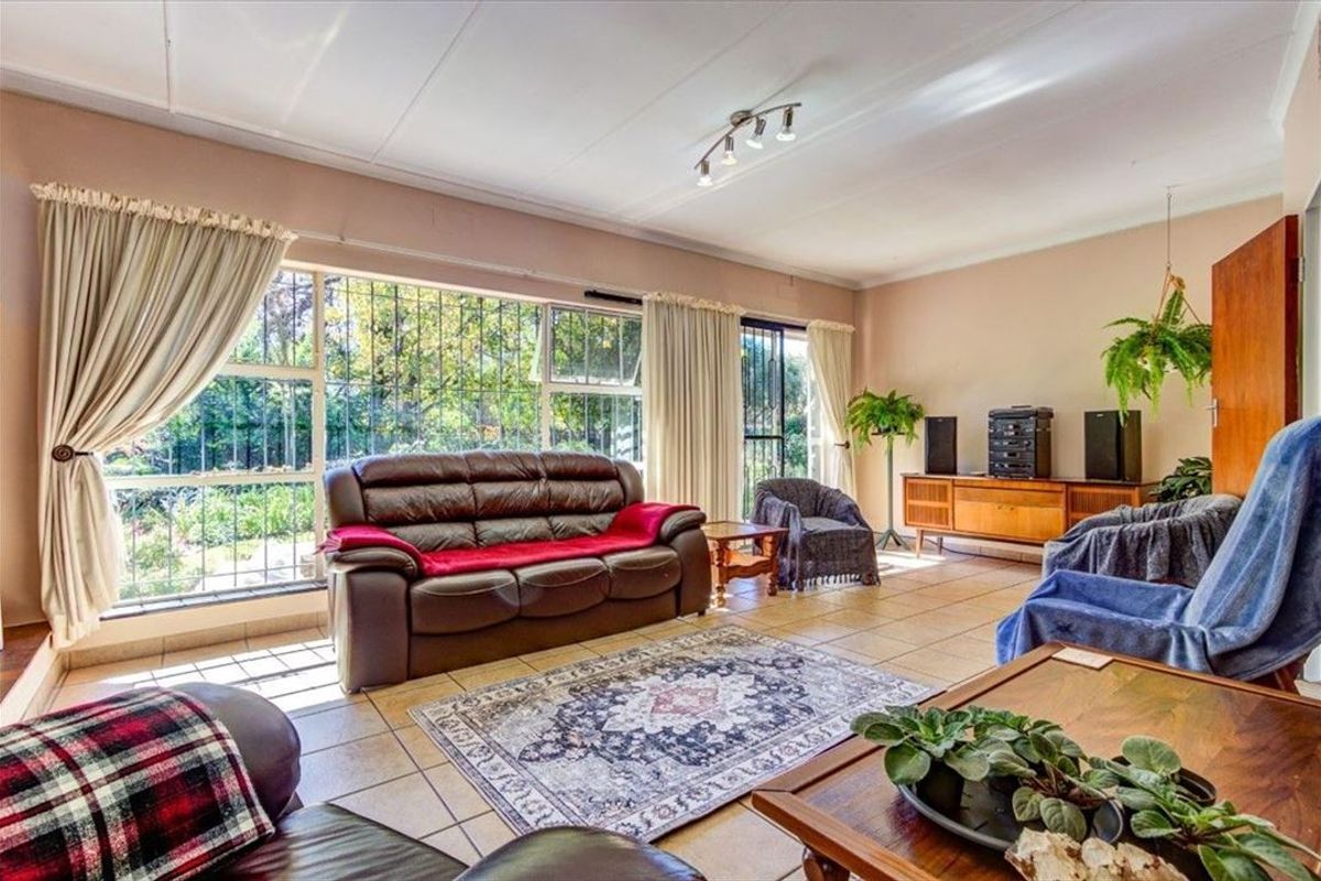 Spacious living room featuring large windows with security bars, tiled flooring, and track lighting, offering a bright and functional living space.