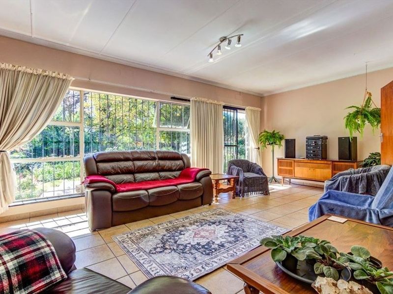 Spacious living room featuring large windows with security bars, tiled flooring, and track lighting, offering a bright and functional living space.