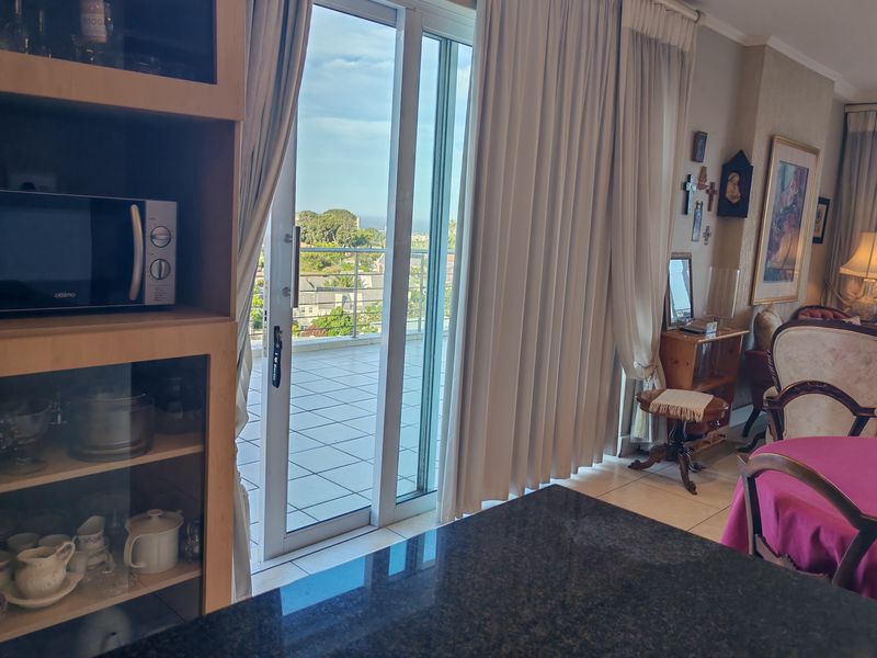 Open plan living area featuring a granite countertop, built-in cabinetry, and large sliding glass doors leading to a tiled balcony with scenic views.