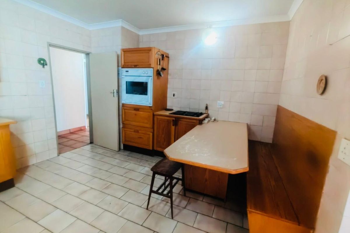 A dated kitchen featuring built-in cabinetry, an integrated oven, hob, and tiled finishes throughout, offering potential for a modern renovation.