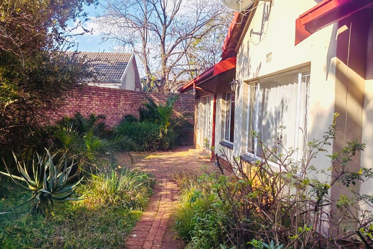Rear garden area featuring a brick paved pathway, established landscaping, and a brick boundary wall, providing a private outdoor space.