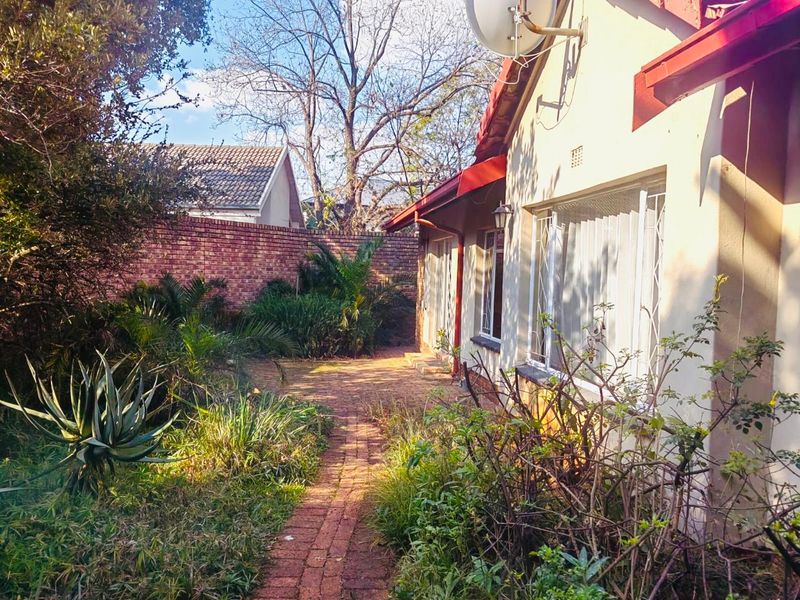 Rear garden area featuring a brick paved pathway, established landscaping, and a brick boundary wall, providing a private outdoor space.