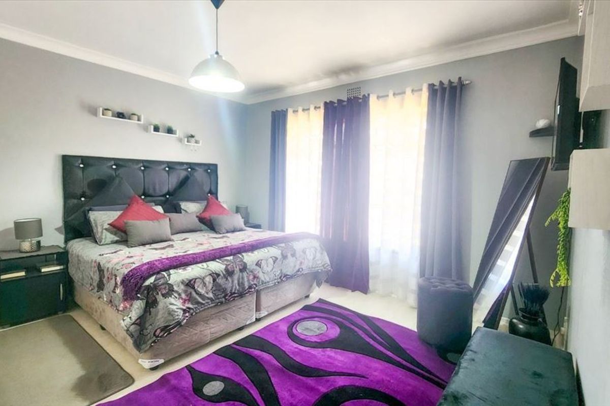 A well-maintained bedroom featuring neutral wall finishes, cove cornicing, and a central pendant light fixture, providing a comfortable and functional sleeping space.