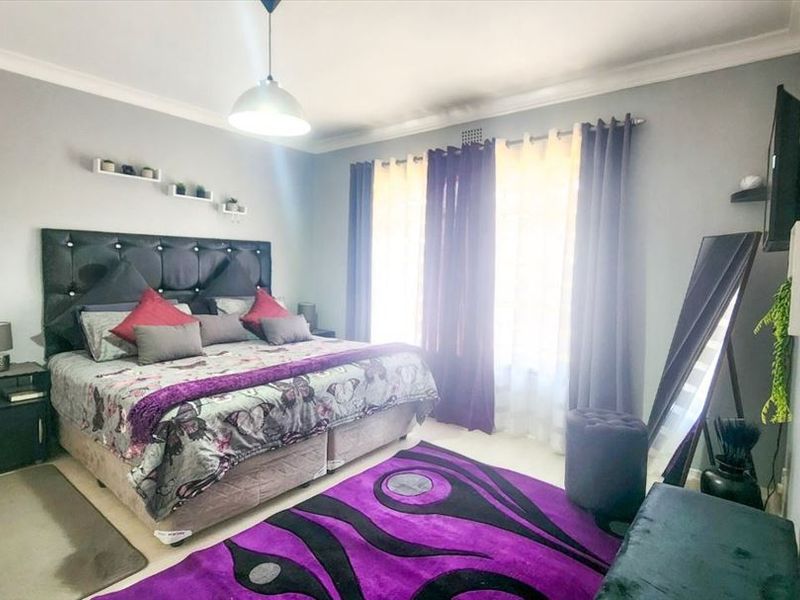 A well-maintained bedroom featuring neutral wall finishes, cove cornicing, and a central pendant light fixture, providing a comfortable and functional sleeping space.