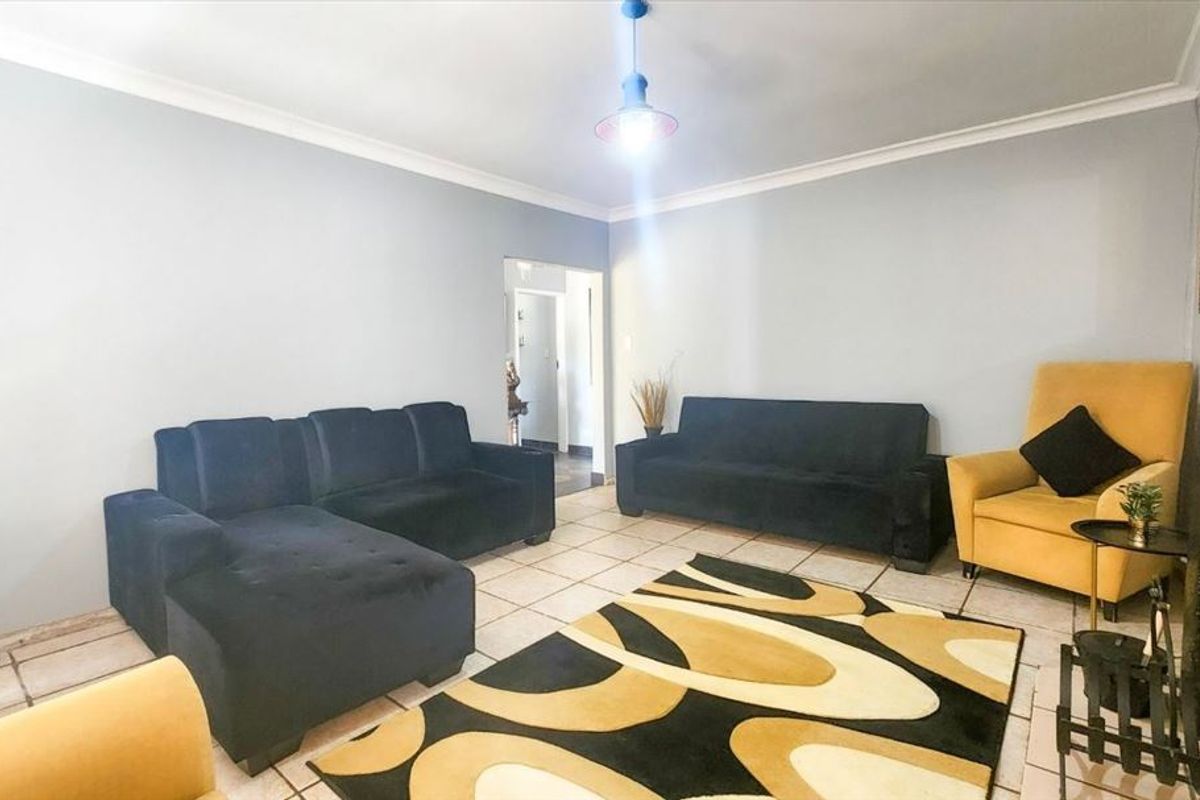 A living room featuring tiled flooring, cove cornicing, and a fireplace, offering a functional space with potential for cosmetic updates.