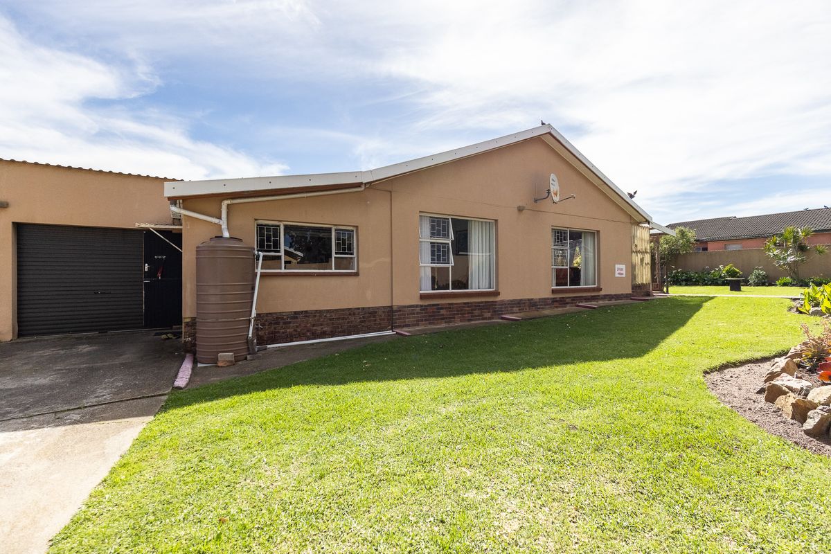 Rear view of the property featuring a single garage, water storage tank, and a well-maintained lawn area.