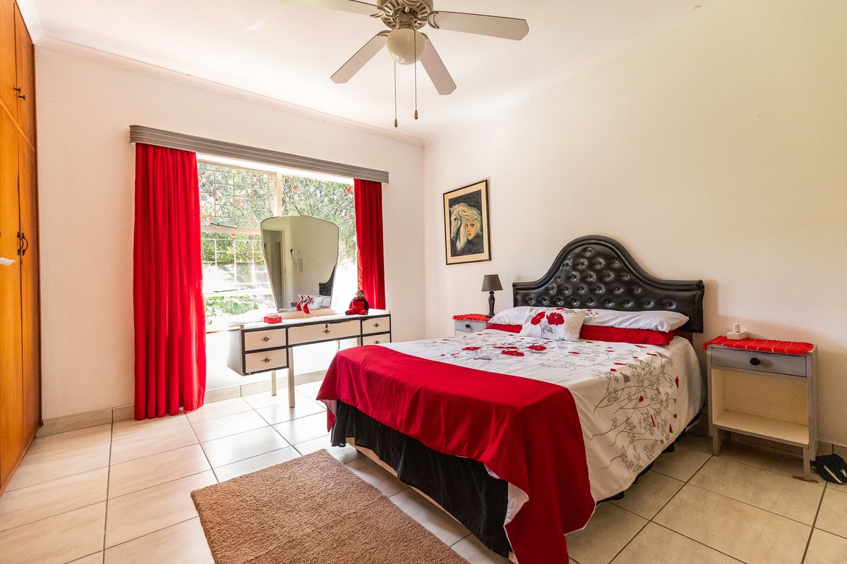 A well-lit bedroom featuring tiled flooring, a ceiling fan, and a built-in wardrobe, offering a functional and comfortable living space.