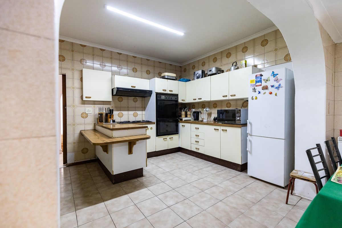 A functional kitchen featuring built-in cabinetry, an integrated oven, extractor fan, and tiled finishes throughout, offering potential for a modern renovation.