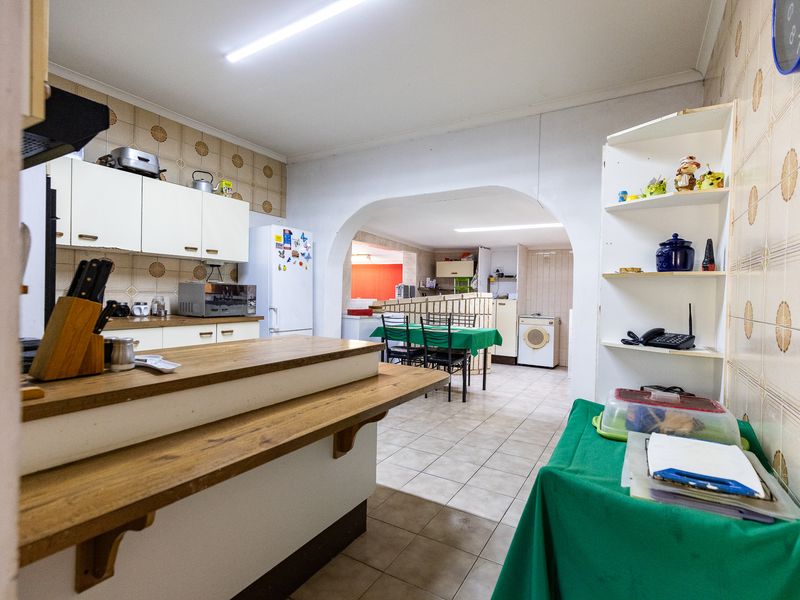 Open plan kitchen and dining area featuring tiled flooring, built-in cabinetry, and a breakfast bar, offering potential for modernization.