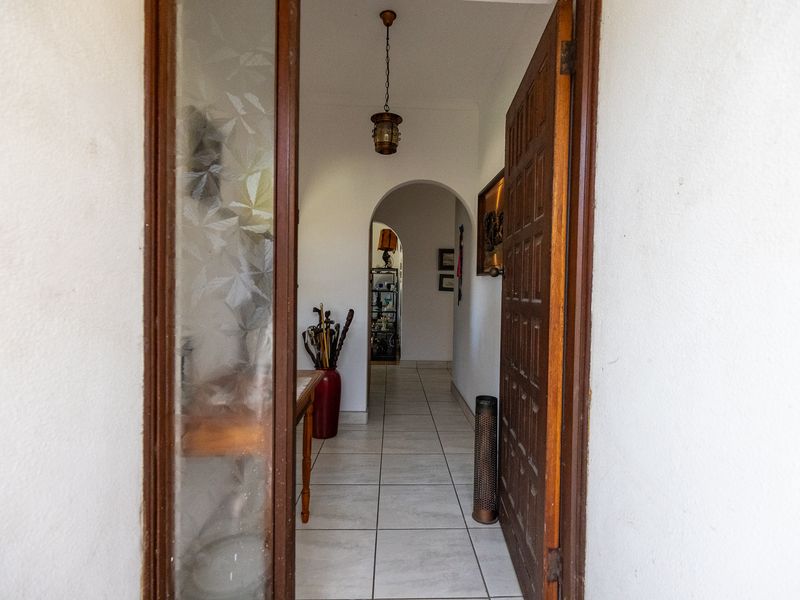 A welcoming entrance hall featuring tiled flooring, an arched transition to the interior, and a classic timber front door with a decorative glass sidelight.