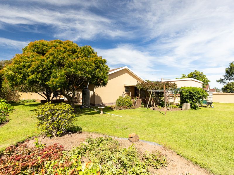 A spacious rear garden featuring a well-maintained lawn, mature trees, and a perimeter wall, providing a private outdoor area.