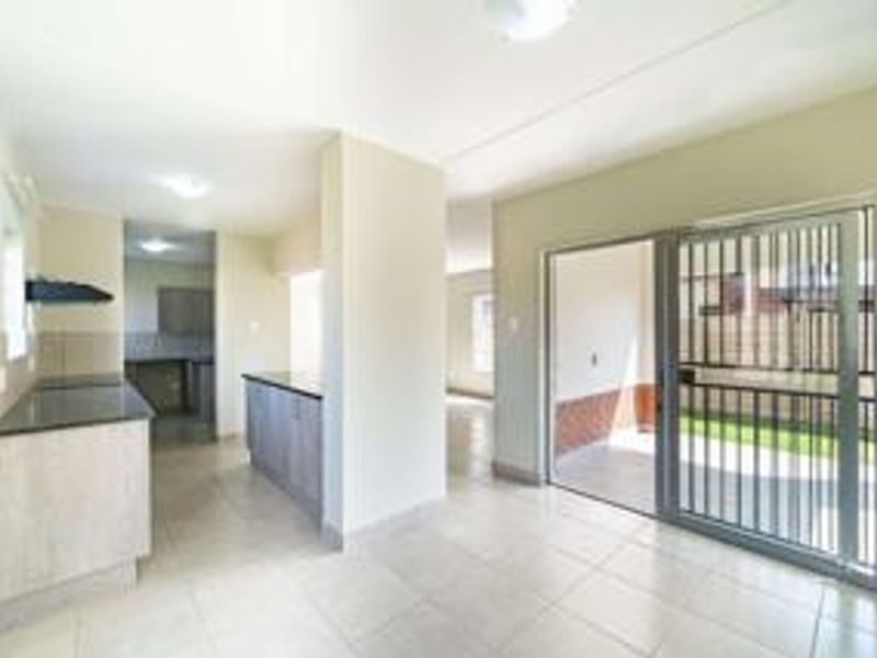 Open plan kitchen and living area featuring tiled floors, granite countertops, and a sliding glass door leading to an outdoor patio space.