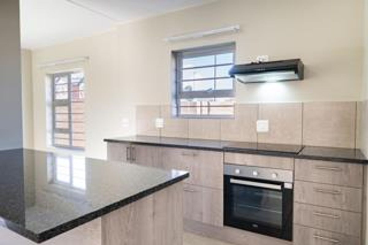 Modern kitchen featuring granite countertops, built-in oven, extractor fan, and ample cabinetry, offering a clean and functional workspace.