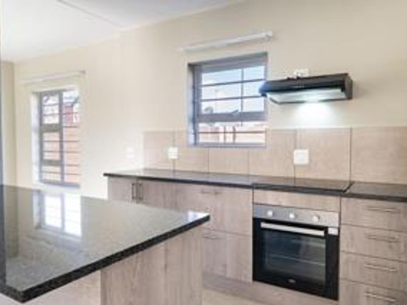 Modern kitchen featuring granite countertops, built-in oven, extractor fan, and ample cabinetry, offering a clean and functional workspace.