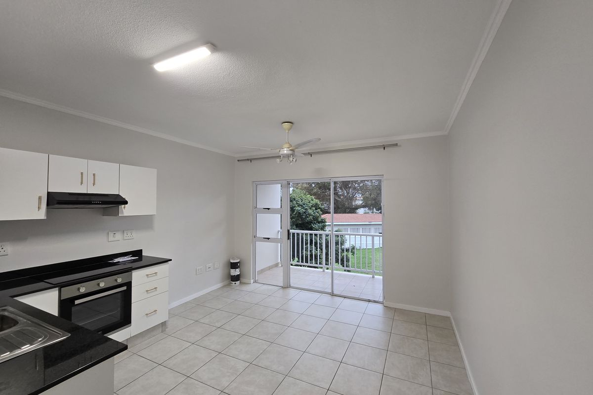Open-plan kitchen and living area featuring tiled floors, modern cabinetry, built-in appliances, and direct access to a private balcony.