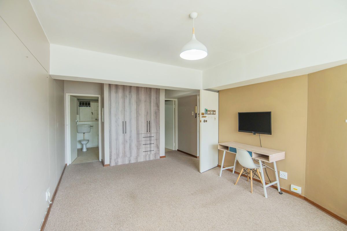 A bedroom featuring built-in wardrobes, neutral carpeting, and an en-suite bathroom access, offering a functional and well-lit living space.