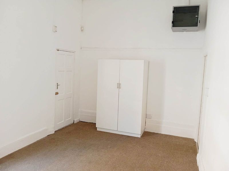 A simple, empty bedroom featuring white walls, a built-in wardrobe, and carpeted flooring.