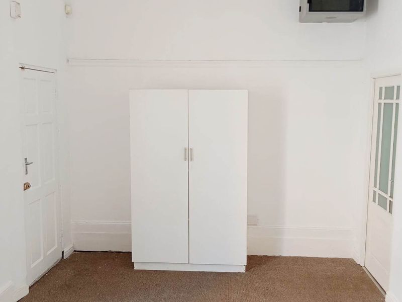An empty bedroom featuring a built-in wardrobe, carpeted flooring, and classic panelled doors, offering a blank canvas for potential renovation or styling.