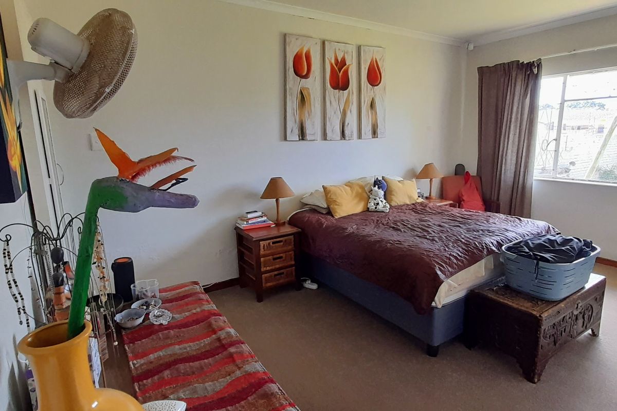 Spacious bedroom featuring carpeted flooring, built-in cupboards, and a large window allowing for natural light.