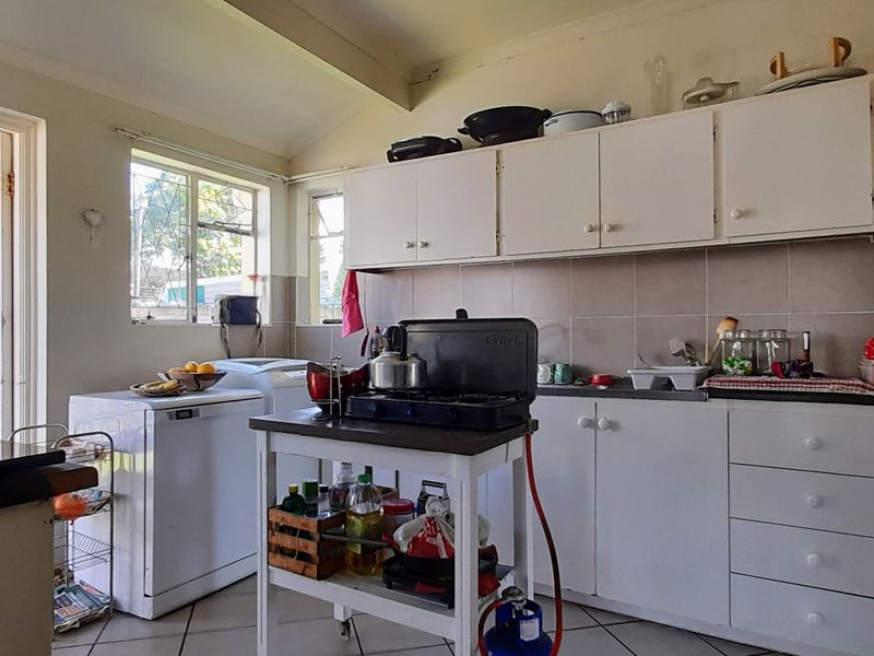 A functional kitchen featuring white built-in cabinetry, tiled backsplash, and tiled flooring, offering a practical layout with potential for modern updates.