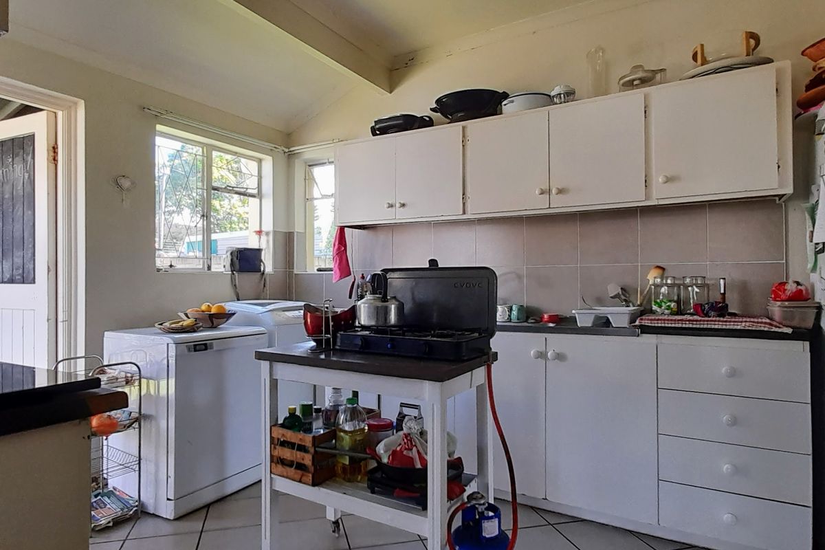 A functional kitchen featuring white built-in cabinetry, tiled backsplash, and tiled flooring, offering a practical layout with potential for modern updates.