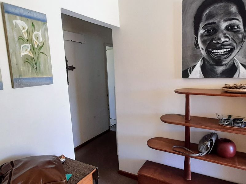 A functional hallway area featuring built-in wooden shelving and access to adjacent rooms.