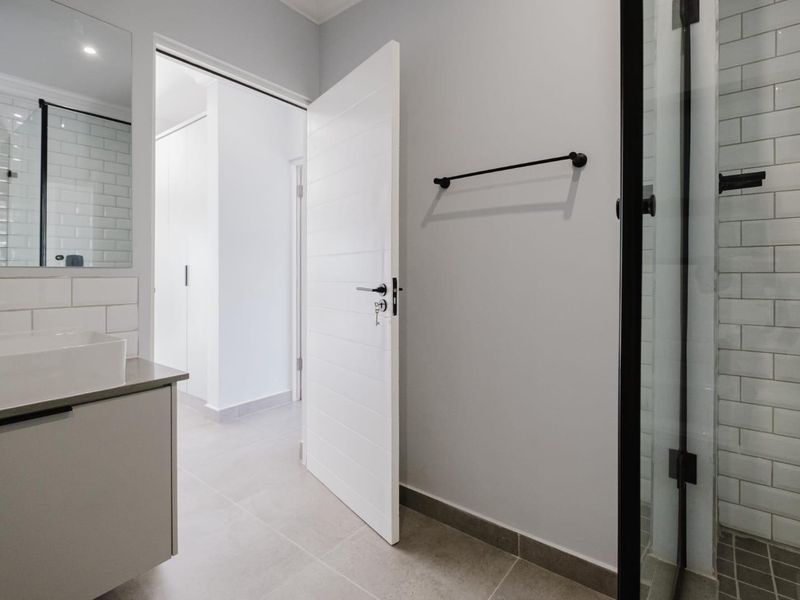 Modern bathroom featuring a sleek vanity with vessel sink, subway tile accents, and a glass-enclosed shower with contemporary black fixtures.