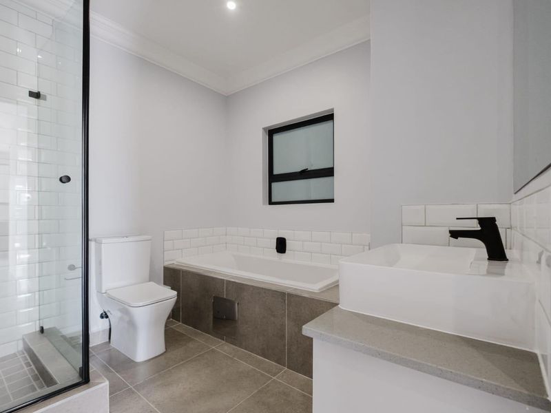 Modern bathroom featuring a glass-enclosed shower, built-in bathtub with subway tile surround, vessel sink with black faucet, and neutral floor tiles.
