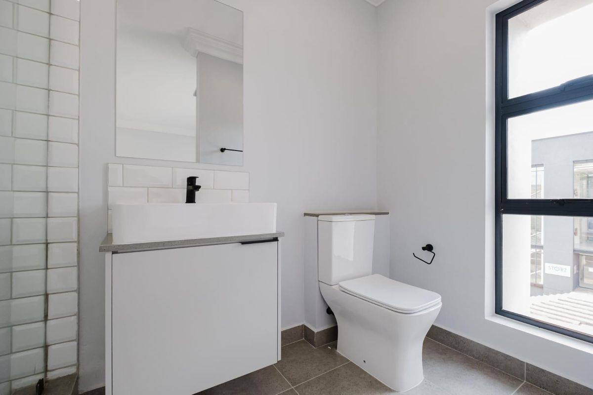 Modern bathroom featuring a sleek vanity with vessel sink, black fixtures, subway tile backsplash, and neutral floor tiles.
