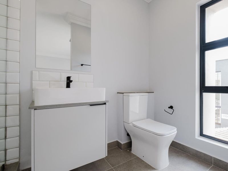 Modern bathroom featuring a sleek vanity with vessel sink, black fixtures, subway tile backsplash, and neutral floor tiles.