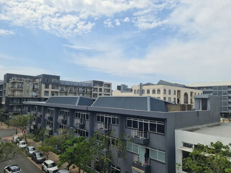 An elevated view of the surrounding apartment complex architecture, showcasing modern building facades, metal roofing, and residential balconies.