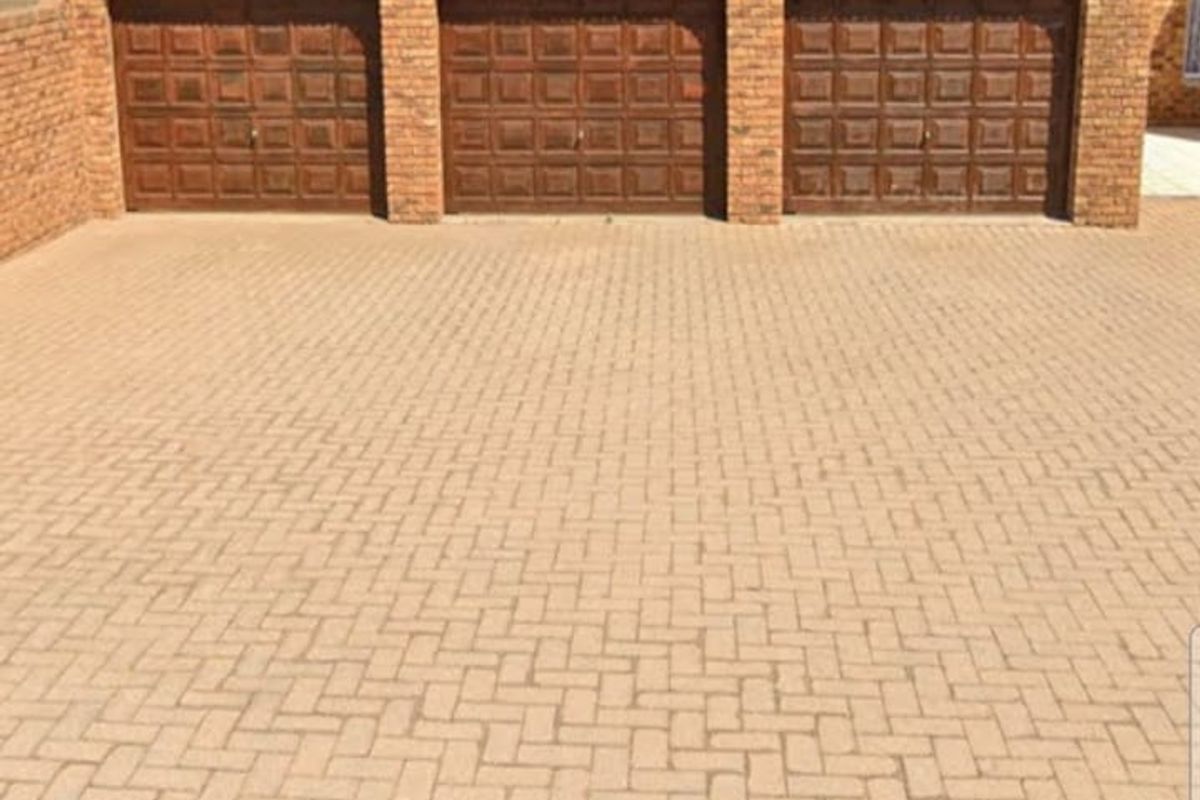 A triple garage featuring dark wood-style doors set within a classic brick facade, complemented by a neatly paved driveway.