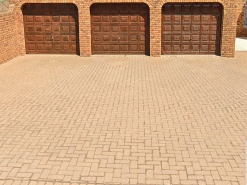 A triple garage featuring dark wood-style doors set within a classic brick facade, complemented by a neatly paved driveway.