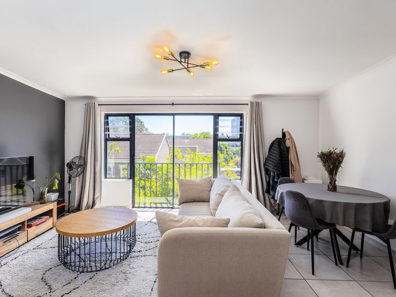 Bright open-plan living and dining area featuring tiled floors, a modern ceiling light, and large sliding doors leading to a balcony.