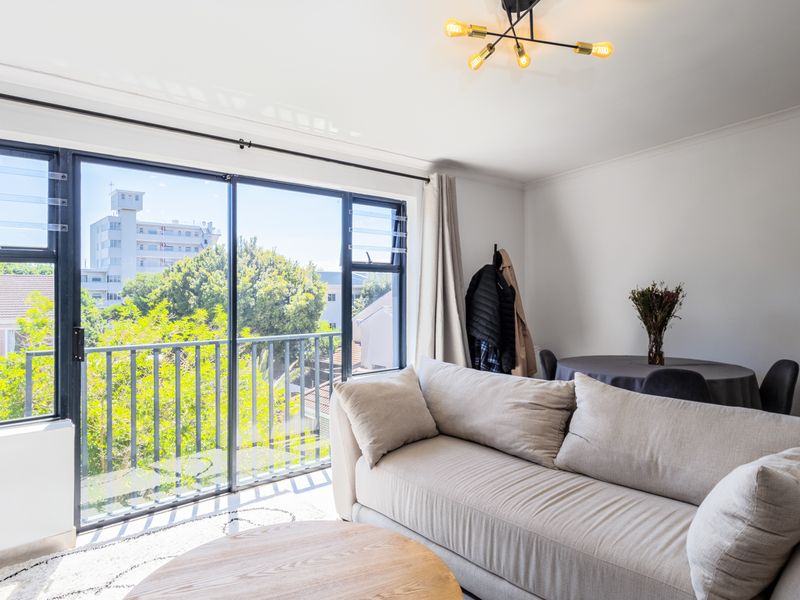 Bright living room featuring large sliding glass doors that open to a balcony, providing ample natural light and pleasant neighborhood views.