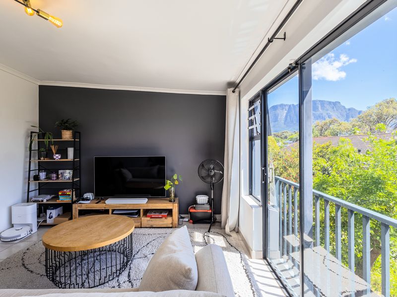 A bright living room featuring large sliding glass doors that open onto a balcony with scenic mountain views.