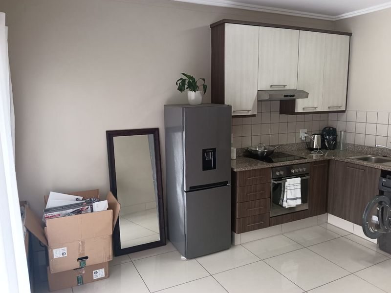 Compact kitchen featuring modern two-tone cabinetry, granite countertops, tiled backsplash, and integrated appliances including an oven and hob.