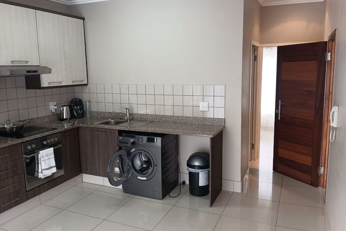 A functional kitchen featuring modern two-tone cabinetry, granite countertops, a tiled backsplash, and integrated appliances including an oven and extractor fan.