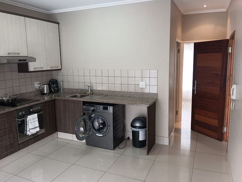 A functional kitchen featuring modern two-tone cabinetry, granite countertops, a tiled backsplash, and integrated appliances including an oven and extractor fan.