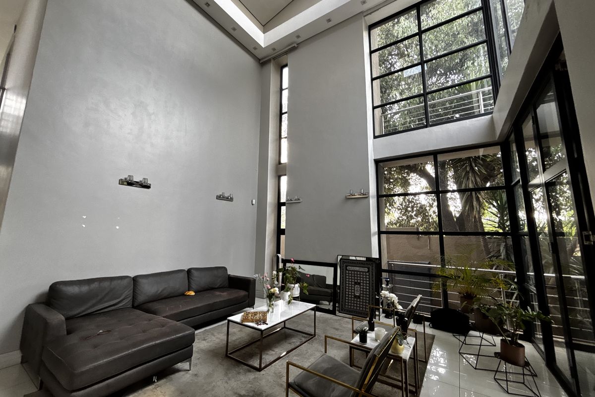 Spacious double-volume living area featuring expansive steel-framed windows that provide abundant natural light and a modern, airy atmosphere.